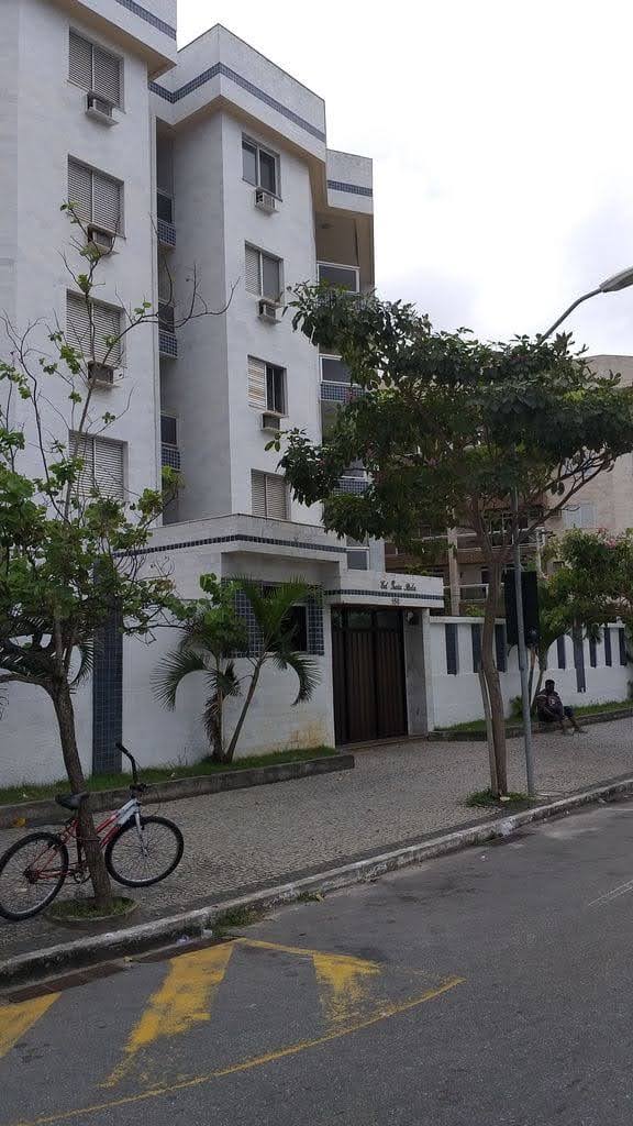 Fachada de prédio residencial com pintura clara e entrada principal.